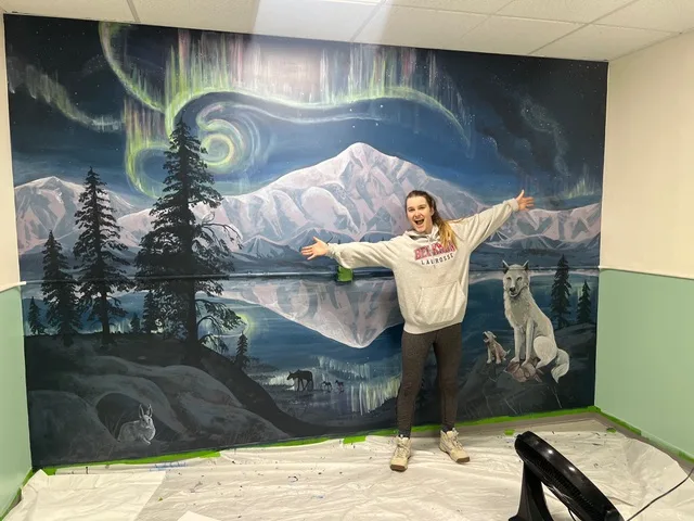 Raea standing in front of an arctic mural