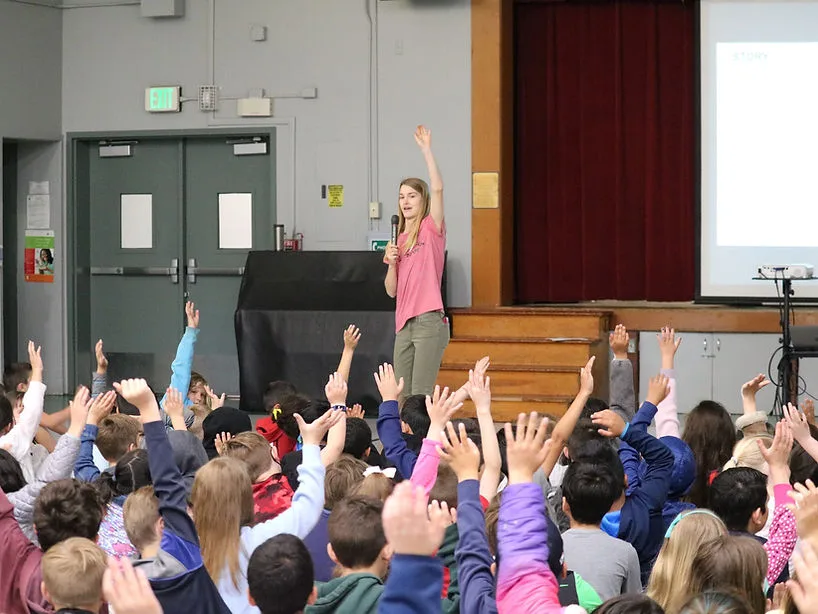 Raea speaking to a group of children in an auditorium
